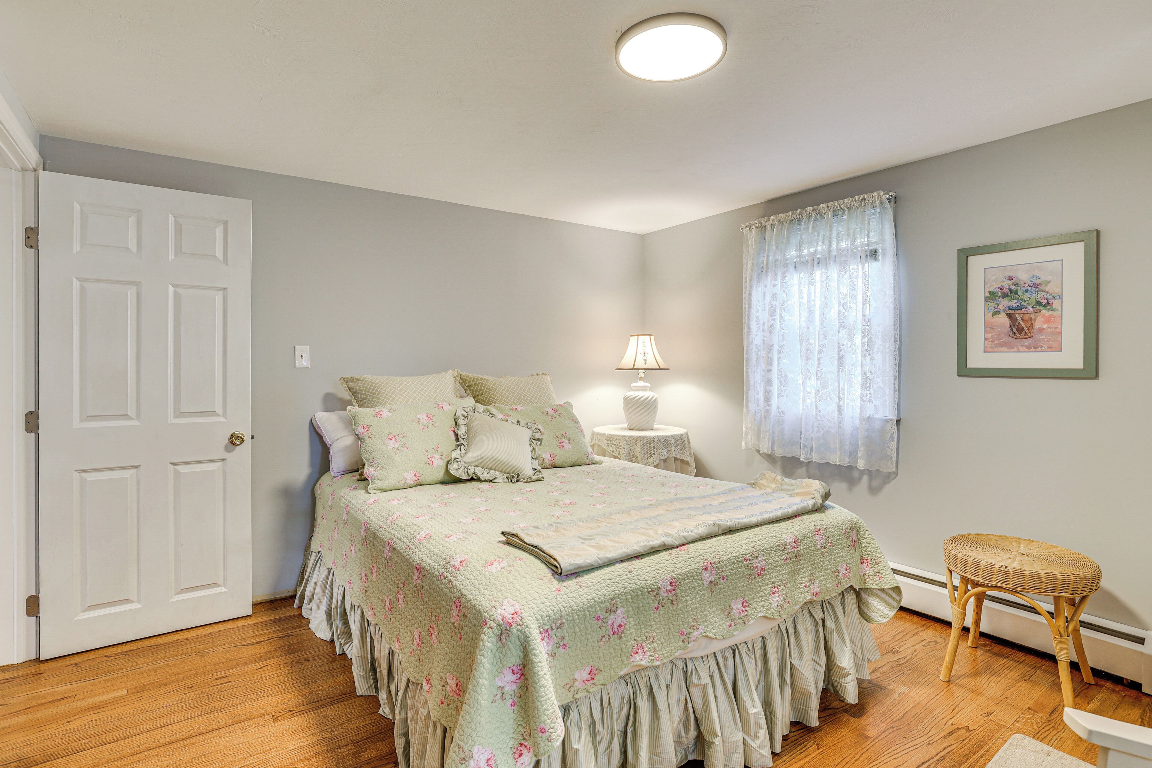 A bedroom with a bed, bedside table, lamp, and a window with curtains.