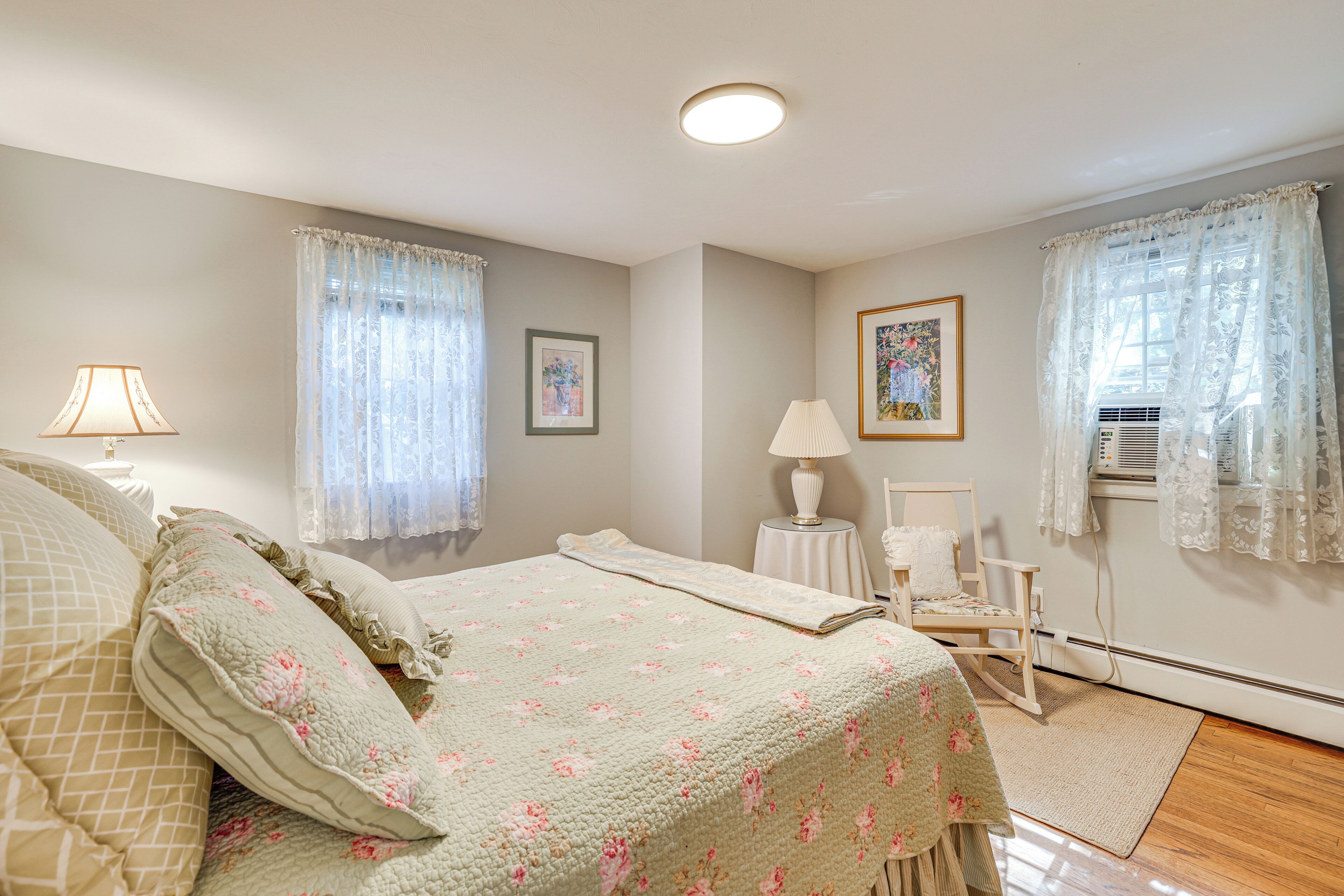 Een slaapkamer met een bed, een stoel, een lamp en een raam met gordijnen.