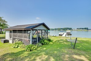 A small, single-story structure with a screened porch, a covered outdoor seating area, and a hammock.