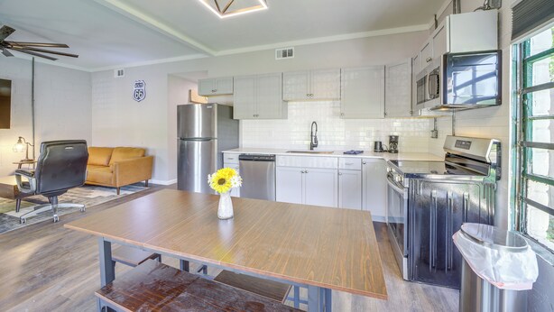 Een moderne keuken met witte kasten, roestvrijstalen apparatuur en een houten eettafel met een bloevas.