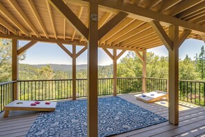 A wooden deck with a blue patterned rug, two wooden benches, and a wooden pergola with a clock. - Hot Tub + Game Room: Family Retreat in Groveland! (Groveland)