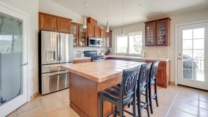 Una cocina con armarios de madera, electrodomésticos de acero inoxidable y una isla grande con taburetes de bar.