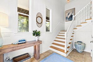 A staircase with wooden steps and white railings, a console table with decorative items, and a large vase. - Private Pool & Hot Tub, 360° Porch, Steps to Beach (Port St. Joe)
