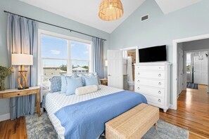 A bedroom with a bed, bedside table, lamp, and a television on a dresser. - Private Pool & Hot Tub, 360° Porch, Steps to Beach (Port St. Joe)