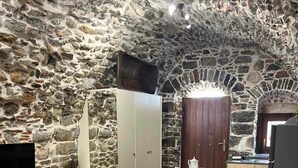 Une pièce chaleureuse avec un mur en pierre, une table à manger en bois, un canapé et un téléviseur.