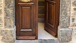 Une porte en bois surmontée d’un arc en pierre, qui donne sur un escalier.