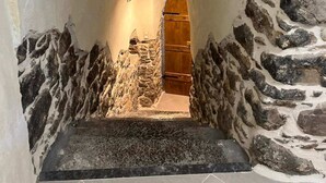 Un couloir aux murs de pierre, avec une porte en bois au bout.