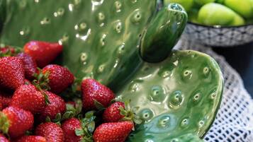 Una planta de cactus con fresas y un tazón de manzanas verdes.
