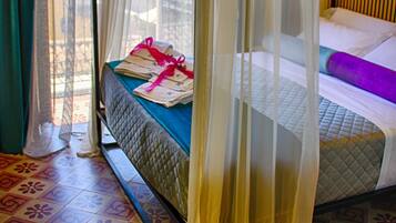 Una cama con dosel, con ropa de cama impecable y una manta púrpura, y vista a un paisaje urbano a través de la ventana.