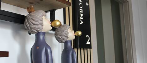 Deux vases en céramique sont posés sur une étagère, et un panneau noir avec l’inscription « NORMA 2 » se trouve à l’arrière-plan.