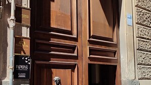 A large wooden double door with a brass handle, flanked by signs for 'Palazzo Merrelli' and 'Roby's Boutique Rooms'. - Roby's boutique rooms (Catania)