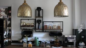 Cozinha com duas luminárias pendentes, prateleiras com potes e uma máquina de café.