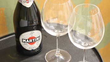 A bottle of Martini champagne and two empty wine glasses on a round table.