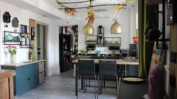 A modern kitchen with a central island, black chairs, and hanging light fixtures.