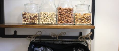 A shelf with glass jars containing nuts and a basket with packaged food items.