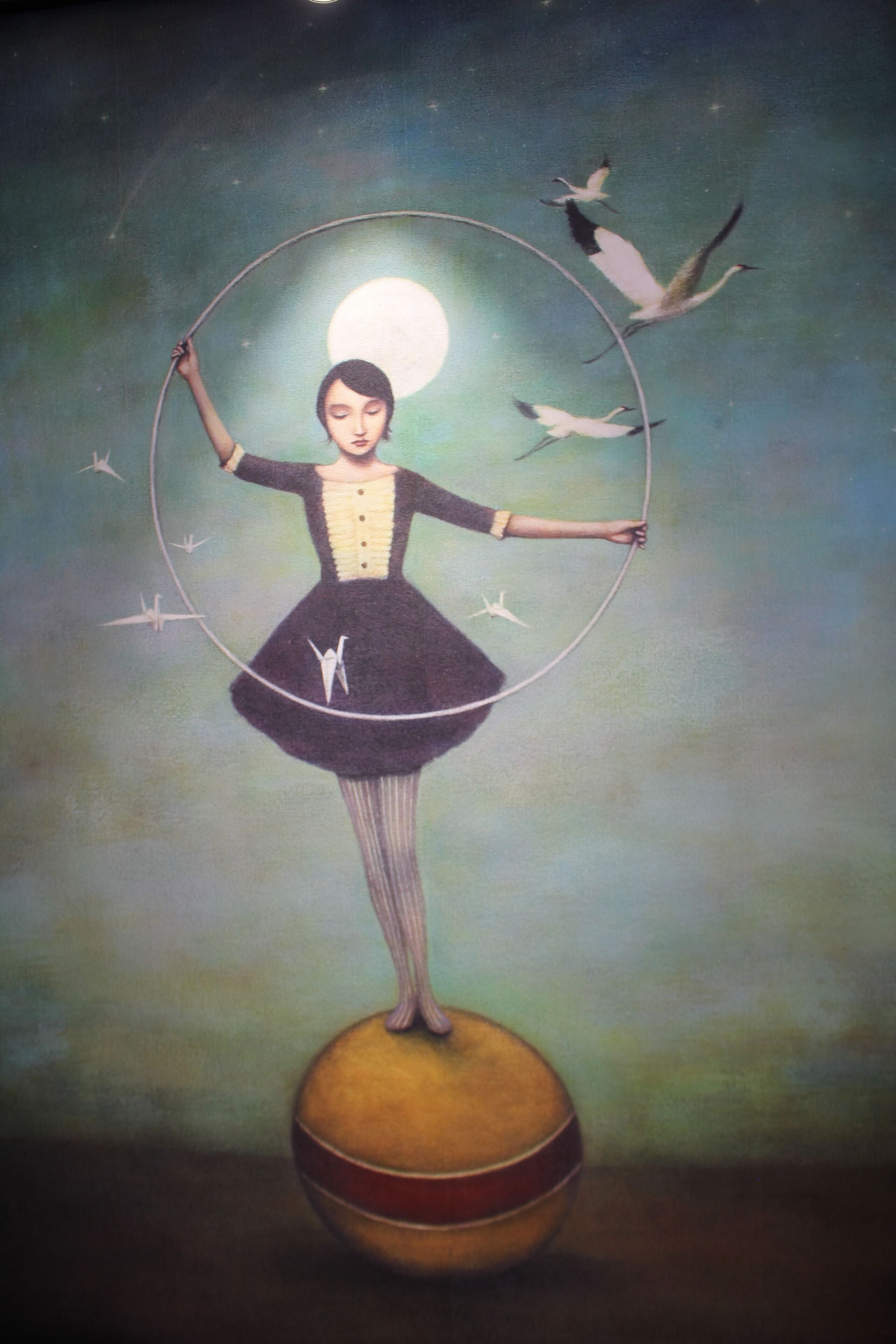 A surreal painting of a woman balancing on a sphere with a hoop, surrounded by birds and a full moon.