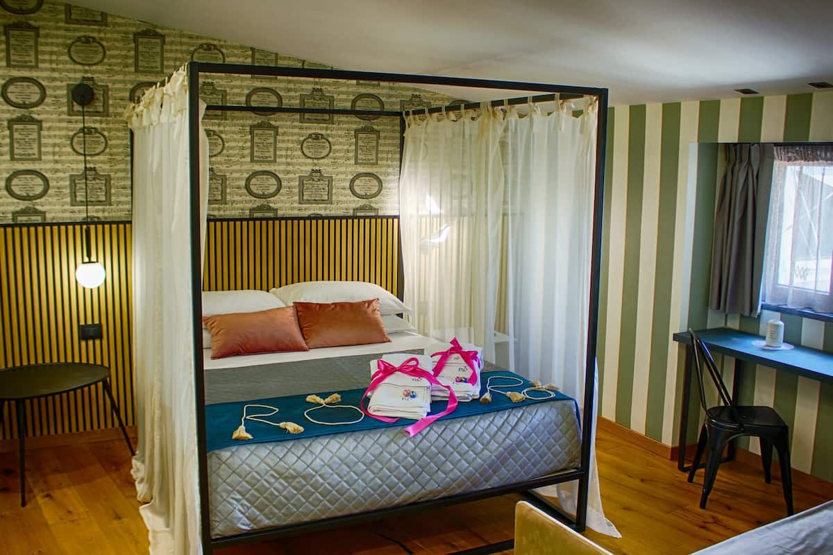 A four-poster bed with a quilted mattress, pillows, and a bedside table with a lamp.