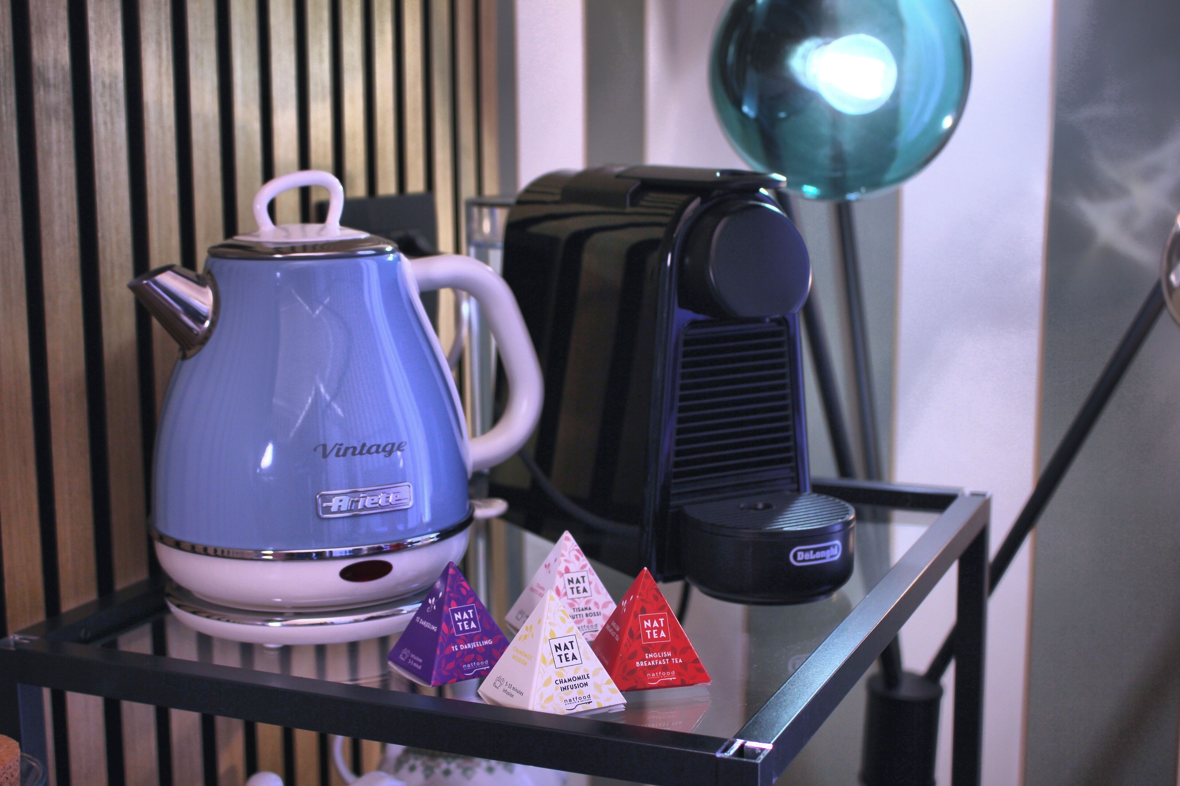 A kitchen area with a blue kettle, a toaster, and three tea bags on a glass table.