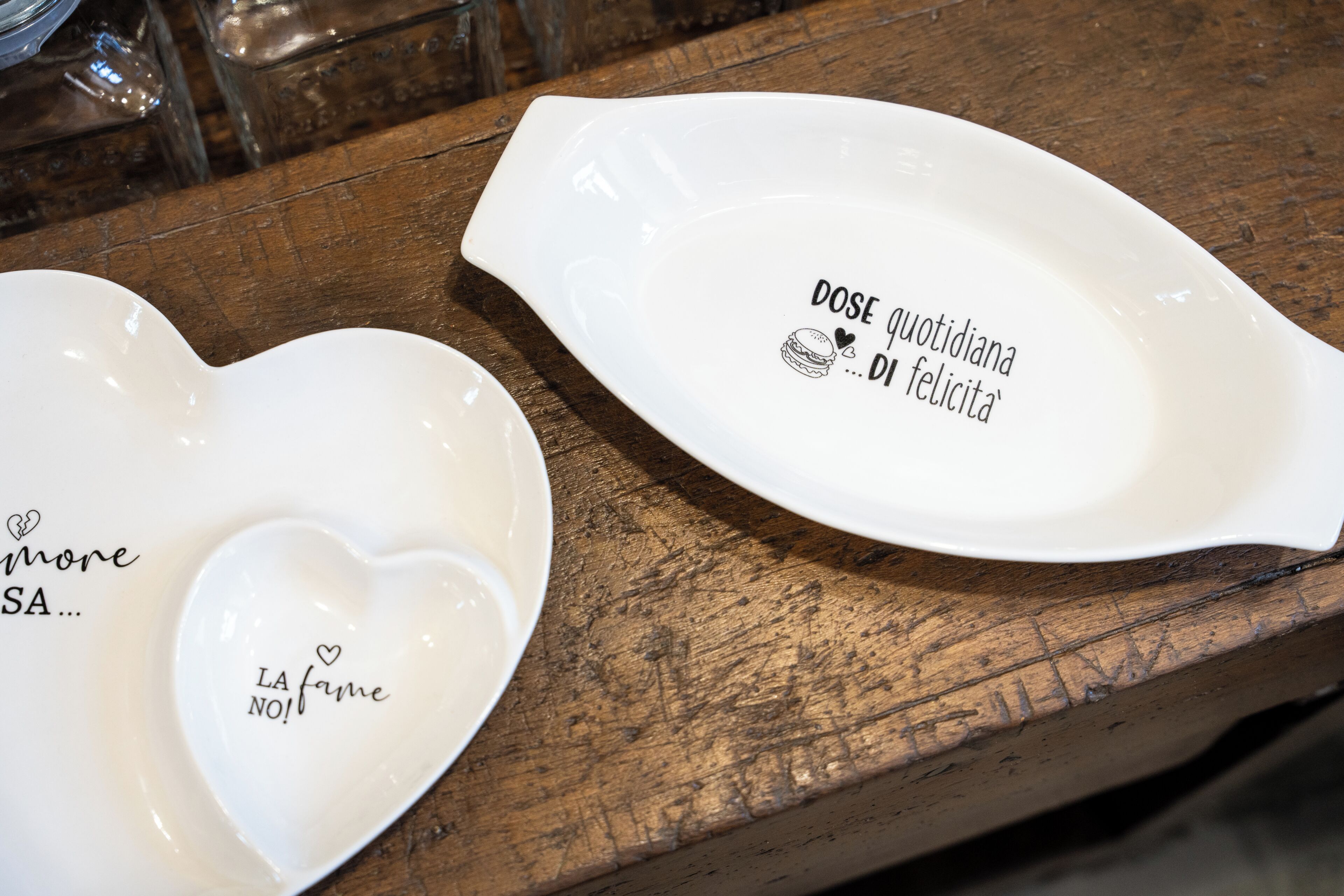 Two white ceramic plates with text on a wooden surface.