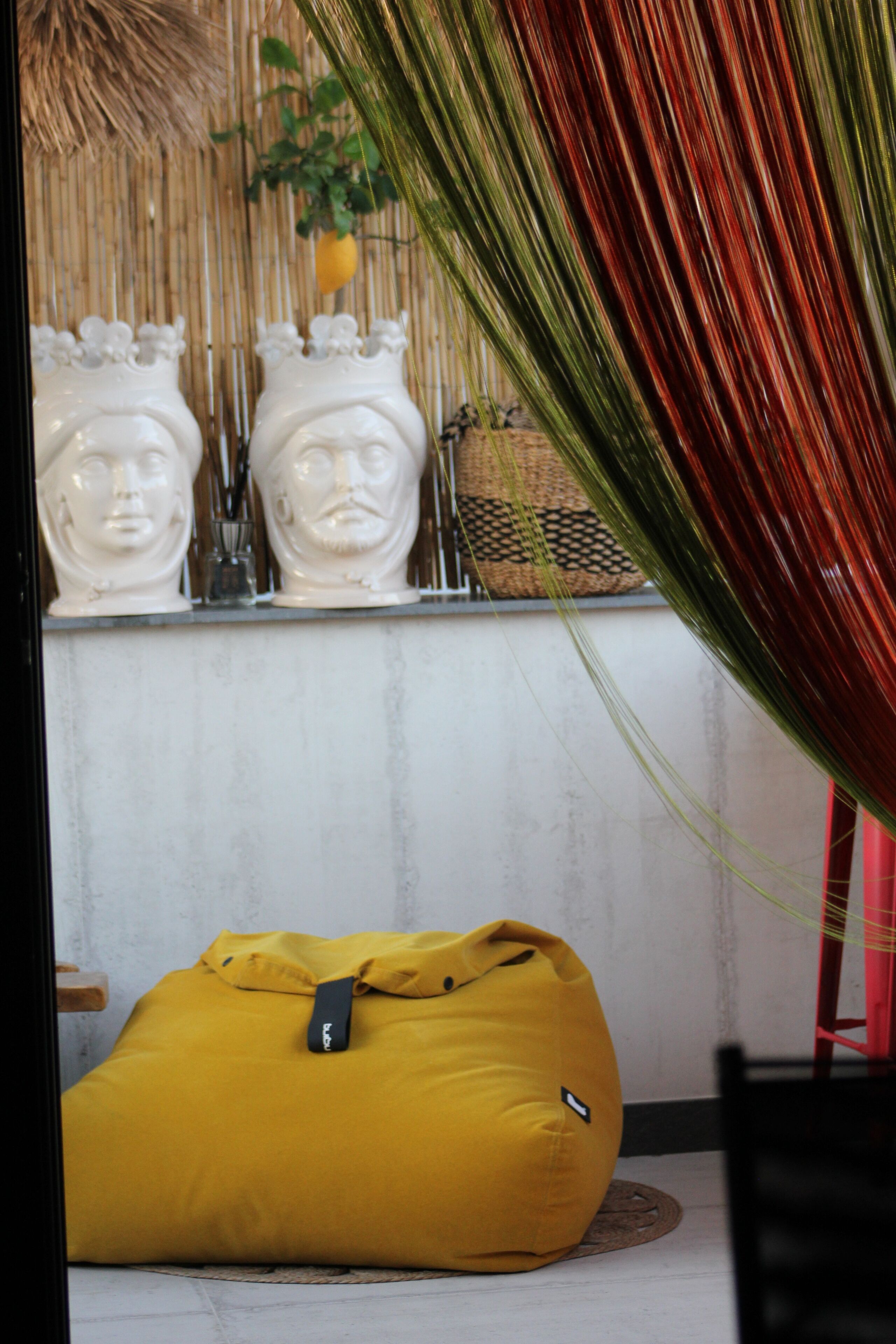 A room with a yellow bean bag chair, a bamboo wall, and a red chair.