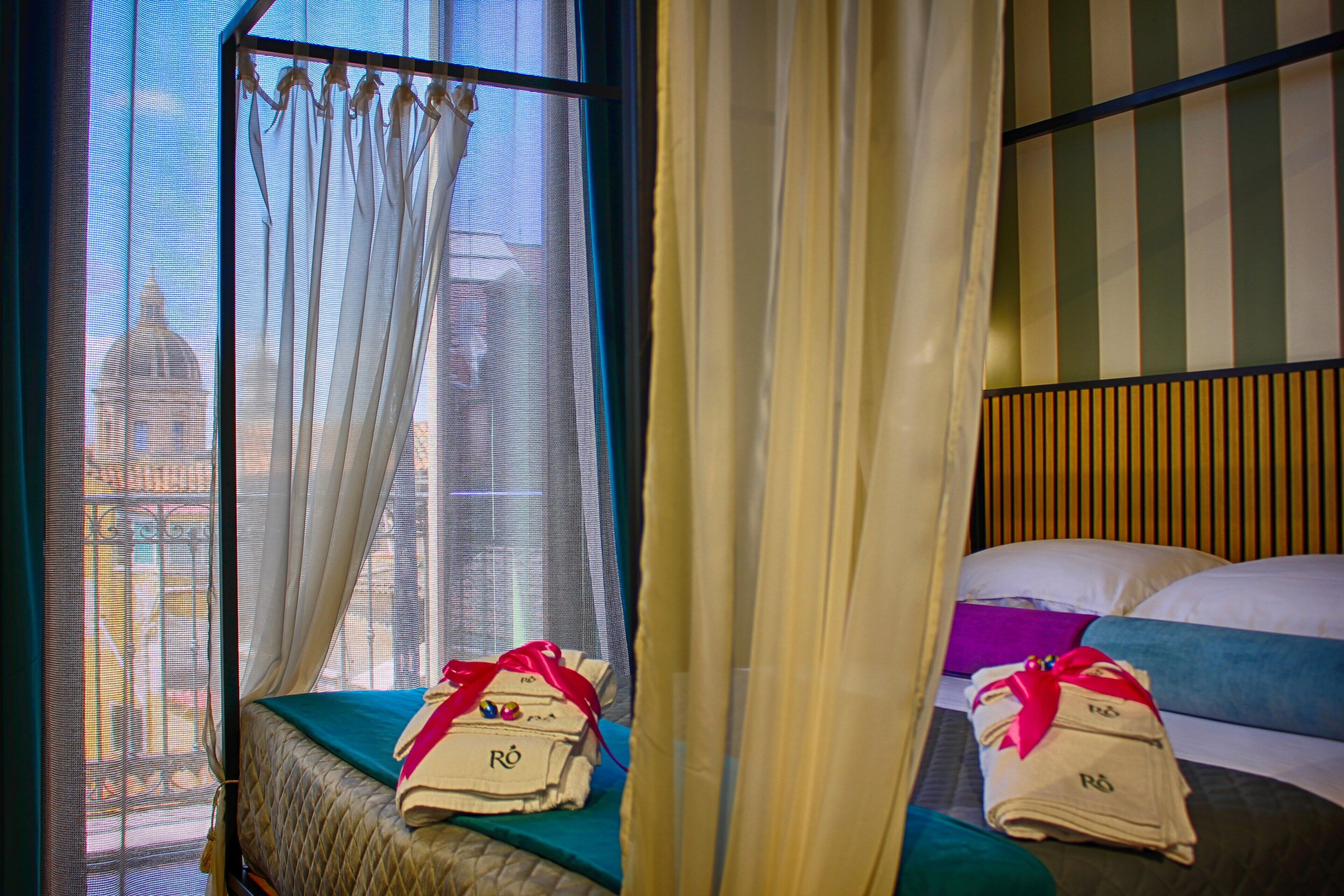 A hotel room with a bed, a window with curtains, and a view of a building.