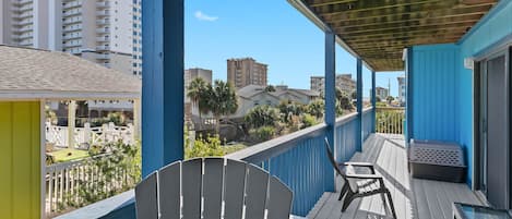 Varanda com vista para a paisagem urbana, uma cadeira branca e uma mesa com churrasqueira.