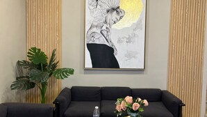 A living room with a black sofa, a coffee table with a water bottle and a tissue box, and a framed artwork on the wall. - Houres Hotel (Cairo)