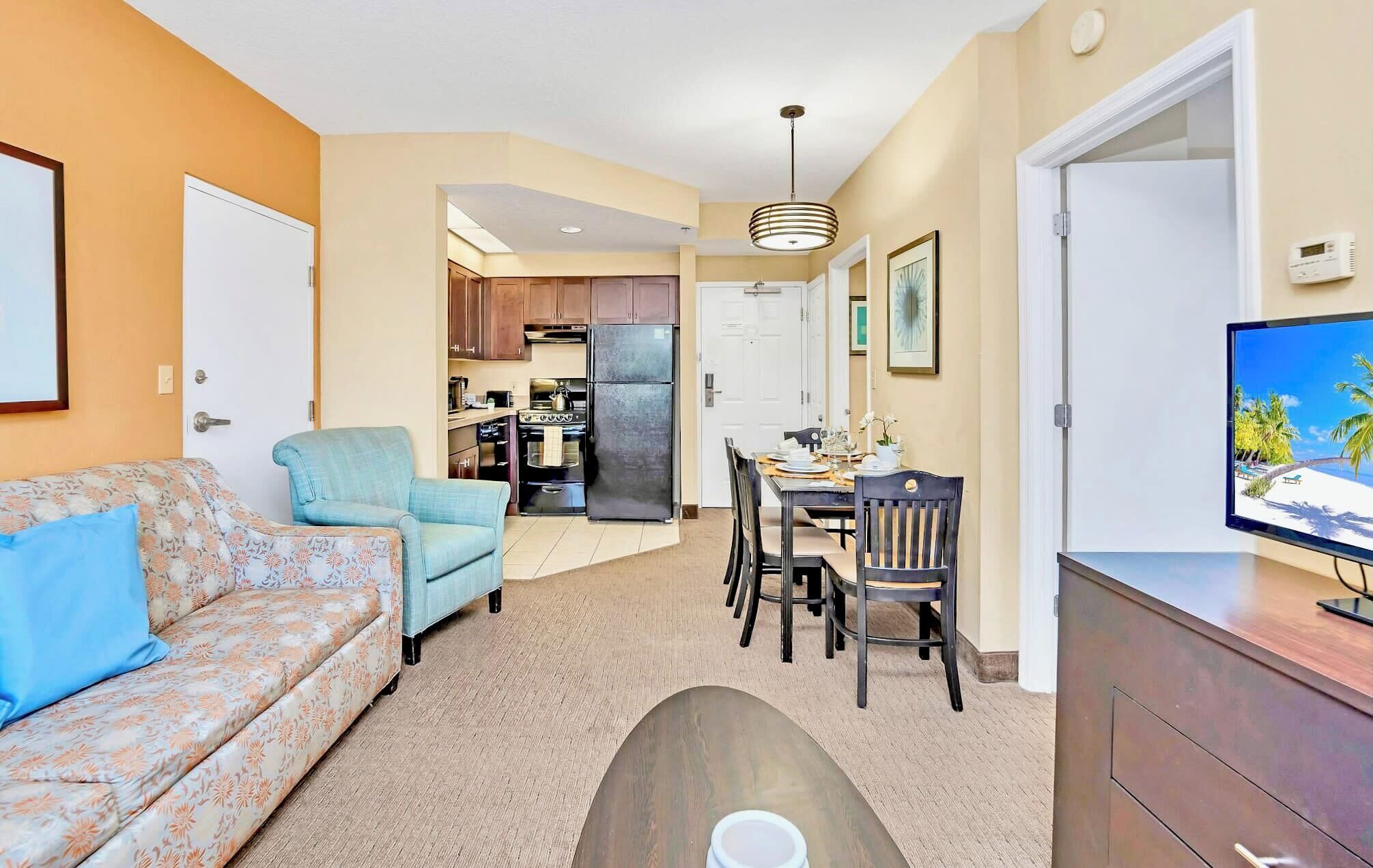 A compact living space with a sofa, a dining table, a TV, and a kitchen area.