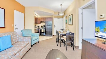 A compact living space with a sofa, a dining table, a TV, and a kitchen area.