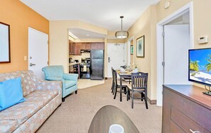 A compact living space with a sofa, a dining table, a TV, and a kitchen area.