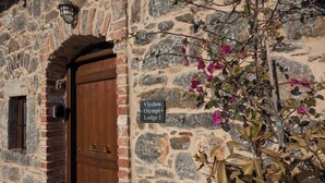 Un bâtiment en pierre avec une porte en bois et une enseigne indiquant « Vlychos Olympi Lodge 1 ».