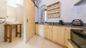 Een keuken met houten kastjes, een spoelbak, een aanrecht met waterkoker en een magnetron.