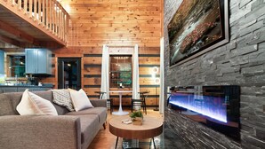 Una sala de estar moderna con techo de madera, pared de piedra y chimenea.