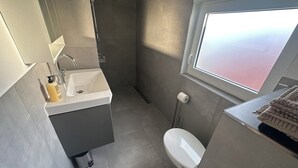A modern bathroom with a sink, toilet, and shower.