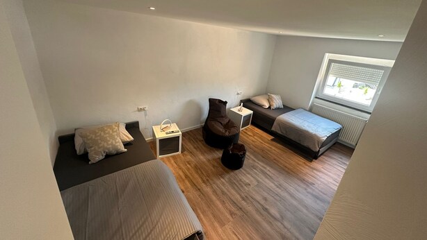 A compact room with two beds, a small table, and a window.