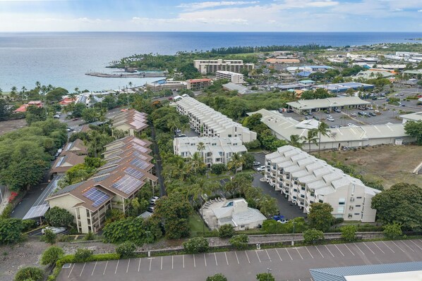 A coastal hotel with multiple buildings, a parking lot, and a view of the ocean.