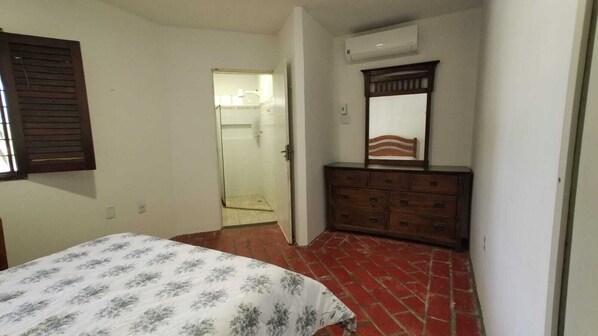 A bedroom with a bed, a dresser, a mirror, and a door leading to a bathroom.