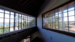 A room with large windows overlooking a lush landscape and a body of water.