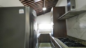 A kitchen with a stainless steel refrigerator, a gas stove, and wooden cabinets.