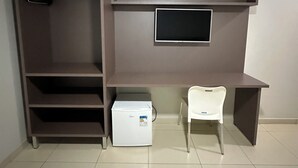 Een kamer met een ingebouwde tv-plank, een witte stoel en een klein wit apparaat op de vloer.