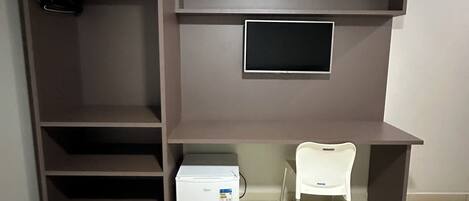 A room with a built-in TV shelf, a white chair, and a small white appliance on the floor.