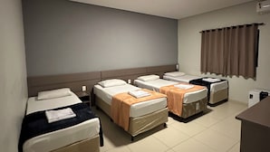 Een hotelkamer met vier eenpersoonsbedden, een bureau en een stoel.