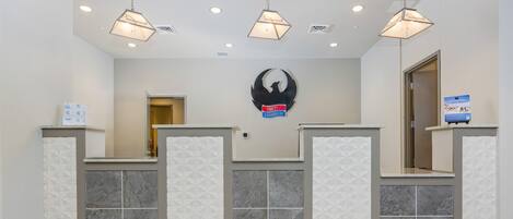 A reception area with a modern design, featuring a geometric tile pattern on the walls and a central logo.