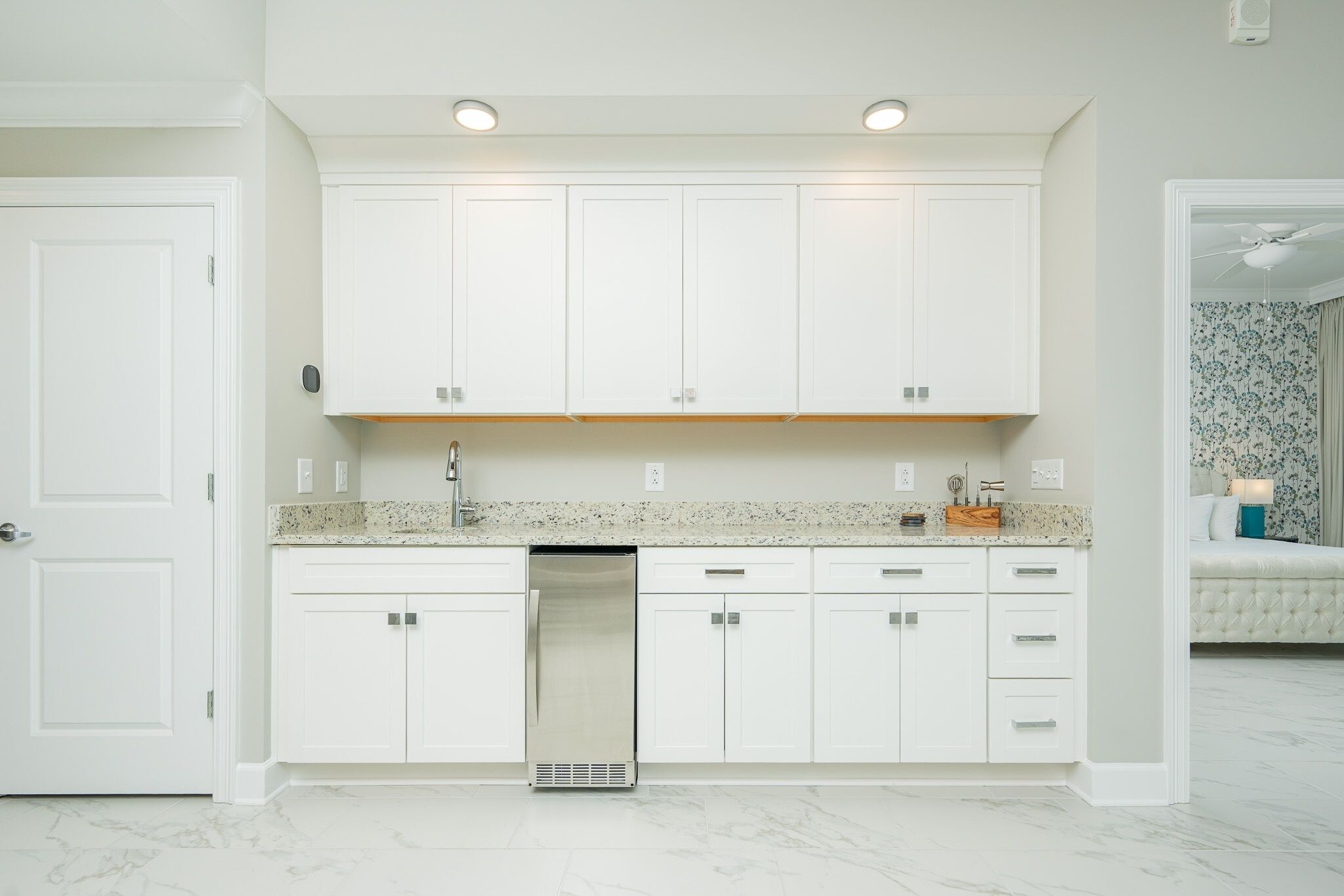 Une cuisine moderne avec des meubles blancs, un lave-vaisselle en acier inoxydable et un plan de travail en granit.