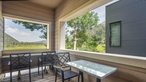 A covered outdoor seating area with a table and chairs, overlooking a scenic landscape.