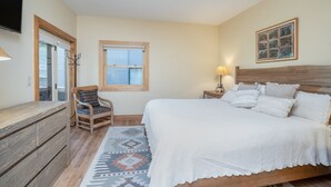 A bedroom with a wooden bed, a chair, a desk, and a window.