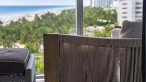Habitación con vistas a la playa y al paisaje urbano, que incluye una silla de mimbre y un sofá.