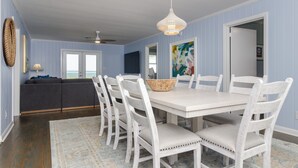 Un espace repas avec une table blanche, des chaises blanches et un luminaire suspendu.