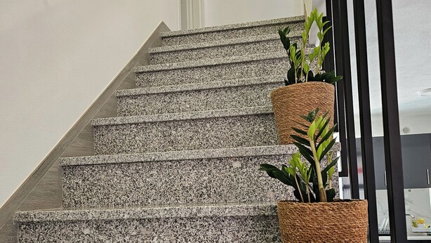 A staircase with granite steps and a handrail, leading to a landing with a door and a round mirror on the wall. - Little House of Heaven (Cortes do Meio)