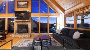 Una sala de estar acogedora con chimenea, asientos confortables y grandes ventanales con vistas al exterior.